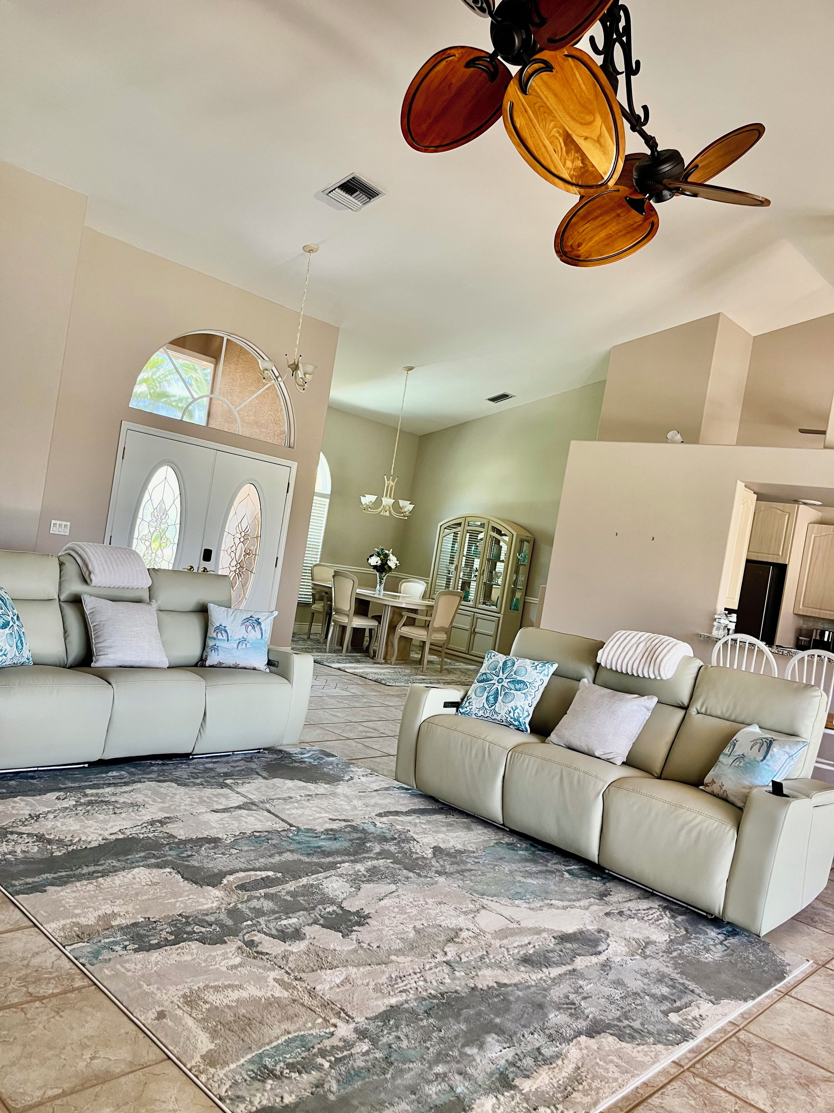 A spacious living room with two sofas, a patterned rug, and a ceiling fan.