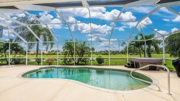 Una piscina con vistas a un campo de golf y palmeras.