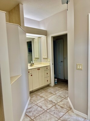 A bathroom with a white vanity, a mirror, and a shower area.