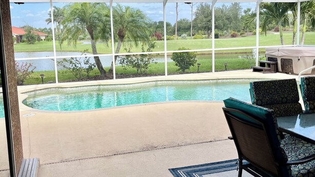 A pool area with a view of a golf course, a covered seating area, and a patio with a table and chairs. - NEW LISTING, Stunning Views, Pool, Hot Tub (Lake Suzy)