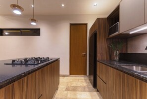 Une cuisine moderne avec des meubles en bois, un plan de travail noir, un four à micro-ondes encastré et un évier en acier inoxydable.