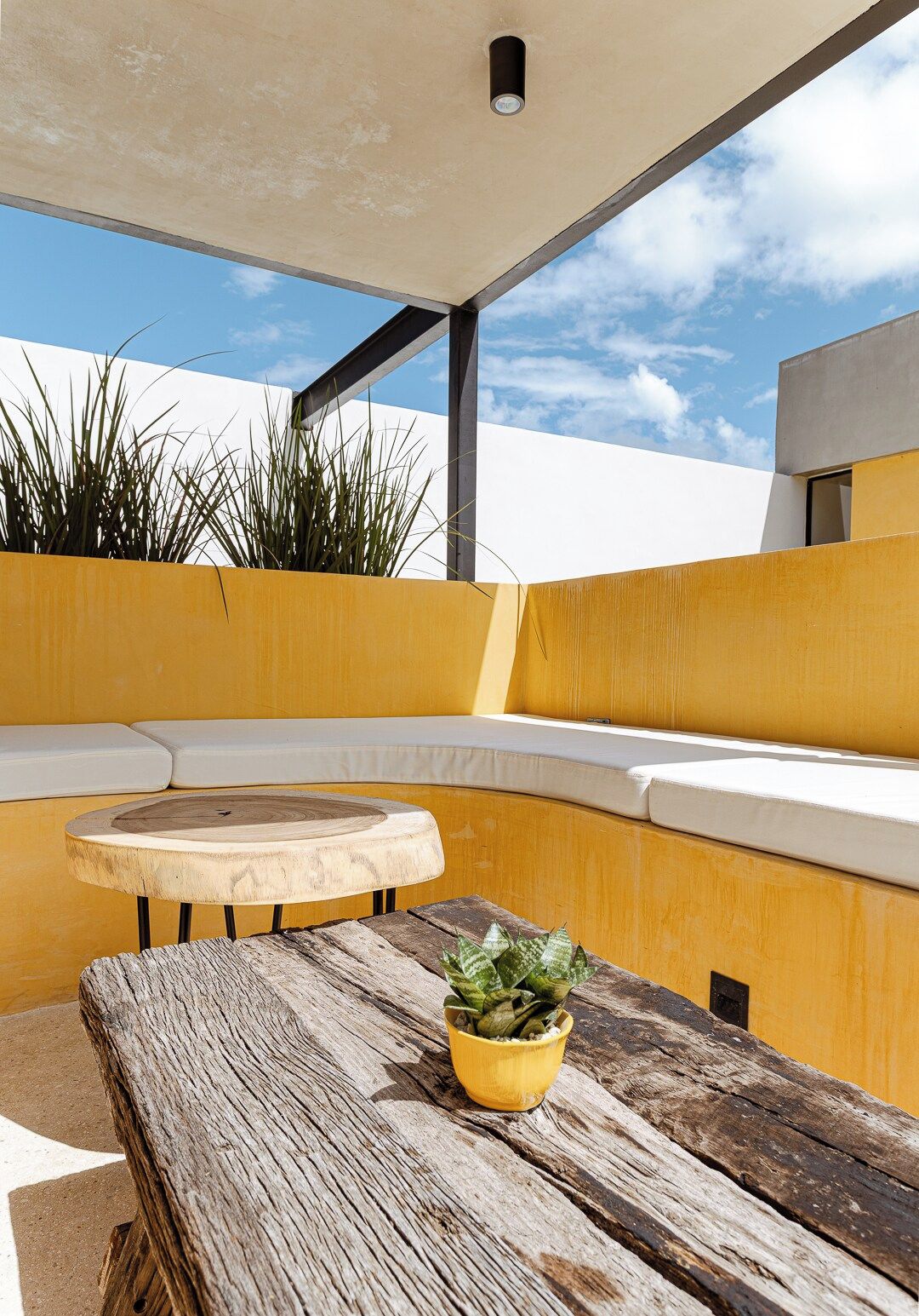 A modern outdoor seating area with a wooden table and a potted plant.
