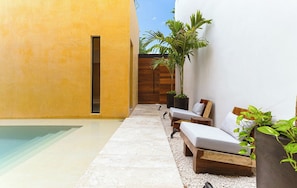 Una zona relax moderna all'aperto con piscina, lettini di legno e piante in vaso.