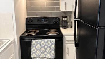 A compact kitchen with white cabinetry, a black stove, and a black refrigerator.