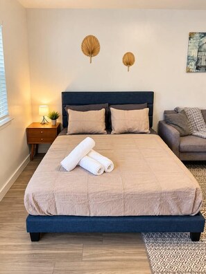A bedroom with a bed, bedside tables, a lamp, and a painting on the wall.