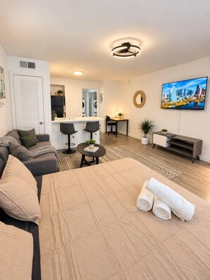 A modern hotel room with a bed, seating area, and a TV. - Bright Studio in Allandale | Near The Domain (Austin)