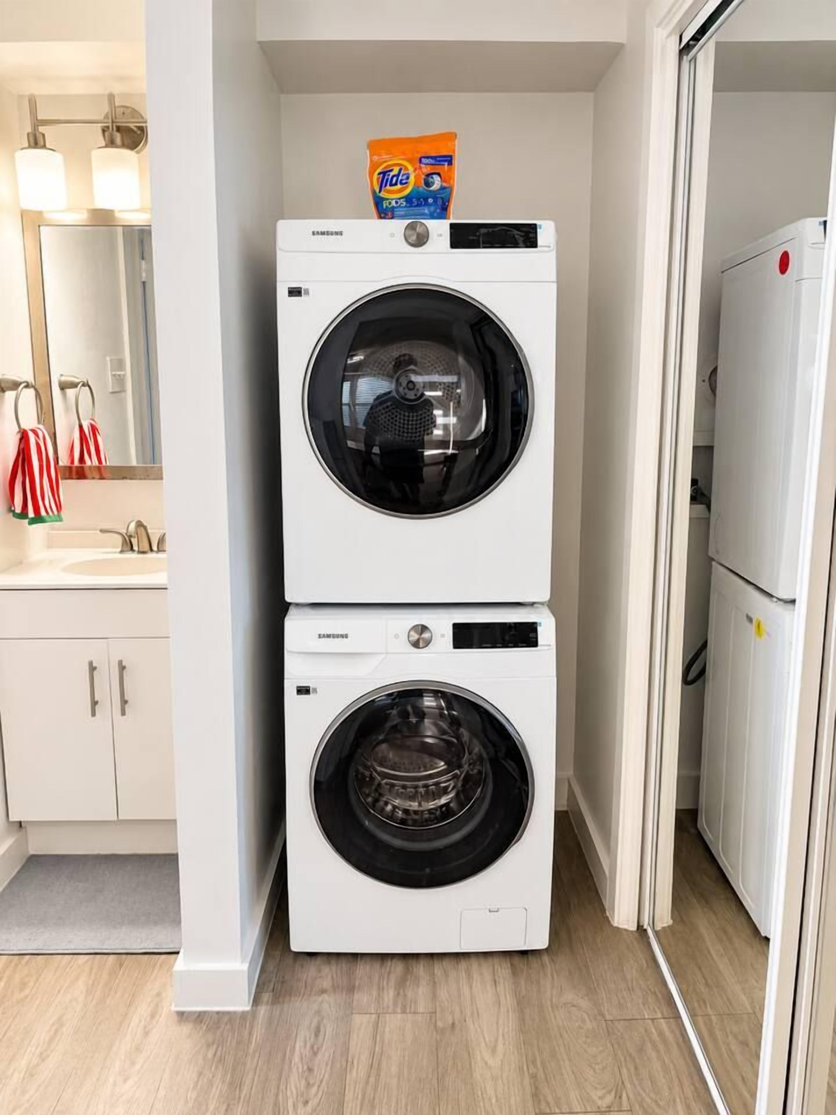 A laundry room with two stacked washing machines and a detergent box on top.
