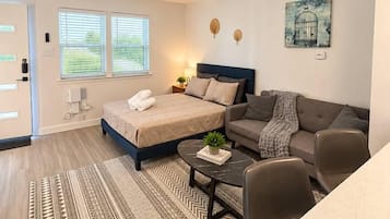 A modern bedroom with a bed, a sofa, a coffee table, and a painting on the wall.