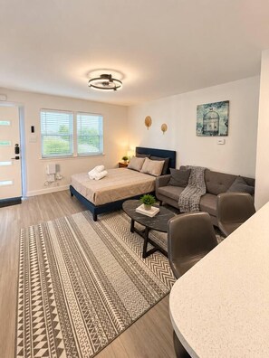 A modern bedroom with a bed, a sofa, a coffee table, and a painting on the wall. - Bright Studio in Allandale | Near The Domain (Austin)