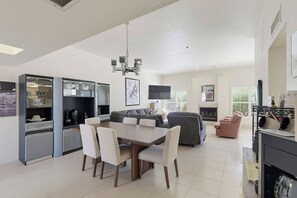 A modern living room with a dining area, kitchen, and seating space.