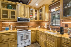 A kitchen with wooden cabinets, a microwave, a stove, and a sink.