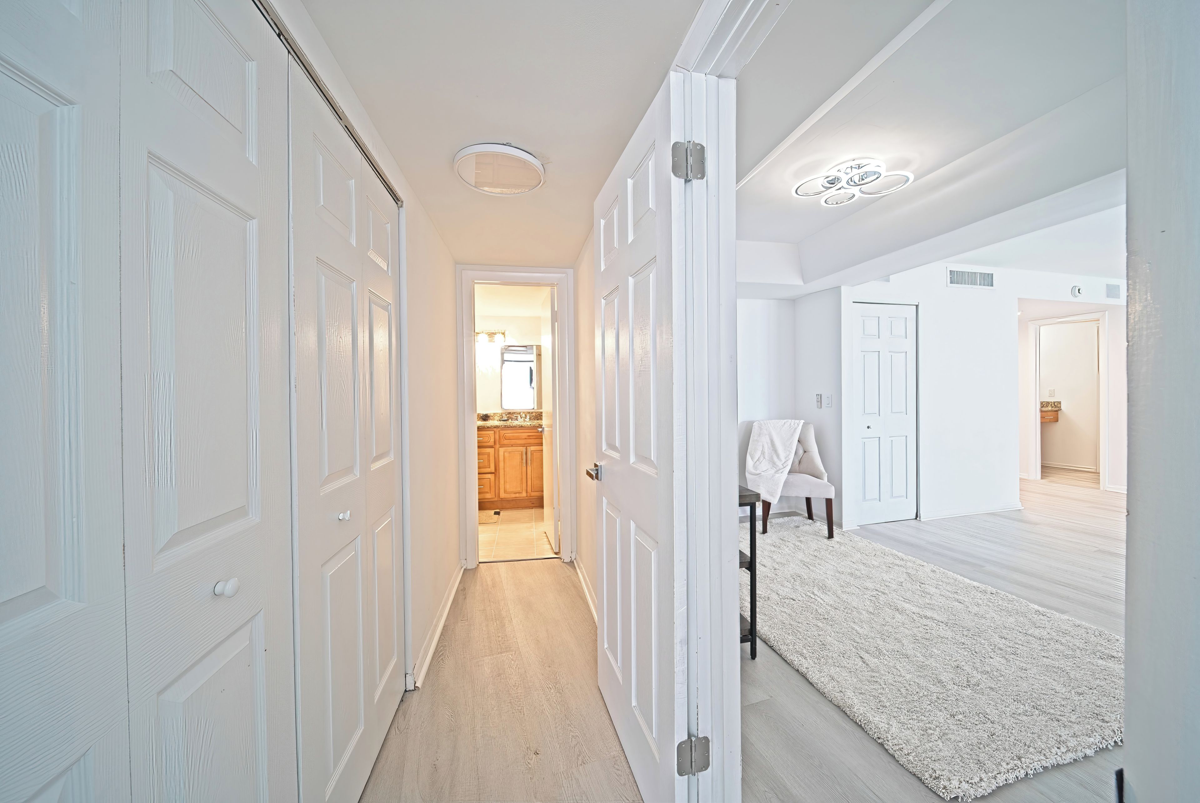 A hallway with white doors, a light-colored carpet, and a ceiling light fixture.