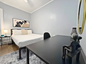 Et moderne hotelværelse med seng, sengebord, lampe og et stort skrivebord med stol.