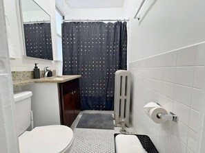 Et lille badeværelse med toilet, håndvask og bruseområde.
