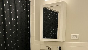 Un baño con inodoro, lavabo y cortina de ducha negra con lunares.