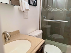 Een badkamer met wastafel, toilet en douchecabine.