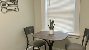 A dining area with a small table and two chairs, a potted plant, and a wall-mounted utensil holder. - 1BR Pad with Homey Feel (Chicago)