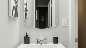 A modern bathroom with a white vanity, a large mirror, and a black soap dispenser. - 1BR Pad with Homey Feel (Chicago)