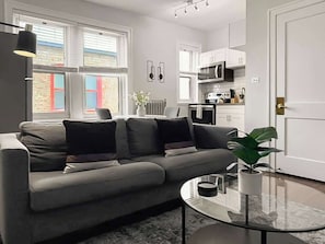 En moderne stue med en grå sofa, et glasbord og en potteplante.