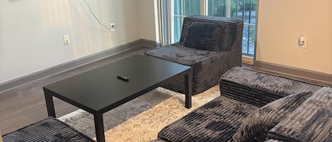 A modern living room with a sofa set, a coffee table, and a TV mounted on the wall.
