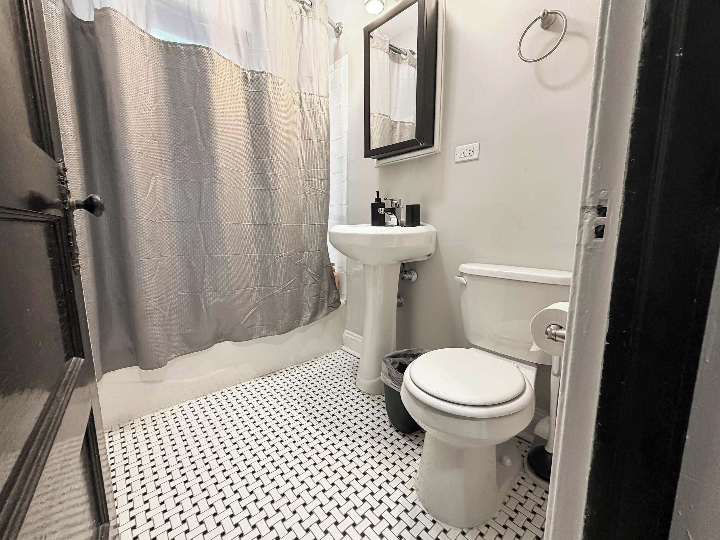 A bathroom with a toilet, sink, and shower curtain.