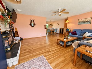 A living room with a fireplace, a ceiling fan, and a dining area with chairs and a table.