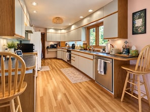 A modern kitchen with wooden flooring, stainless steel appliances, and a large window providing natural light. - Hot tub, private bridge, large patio, and secret garden property to explore (Moscow)