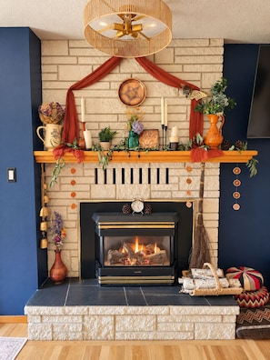 A fireplace with a mantel decorated with candles, a clock, and various ornaments.