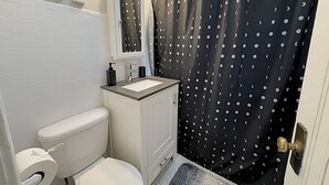 Une salle de bain équipée de toilettes, d’un lavabo et d’un rideau de douche à motifs à pois.