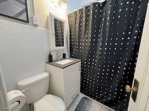 Een badkamer met toilet, wastafel en douchegordijn met stippen.