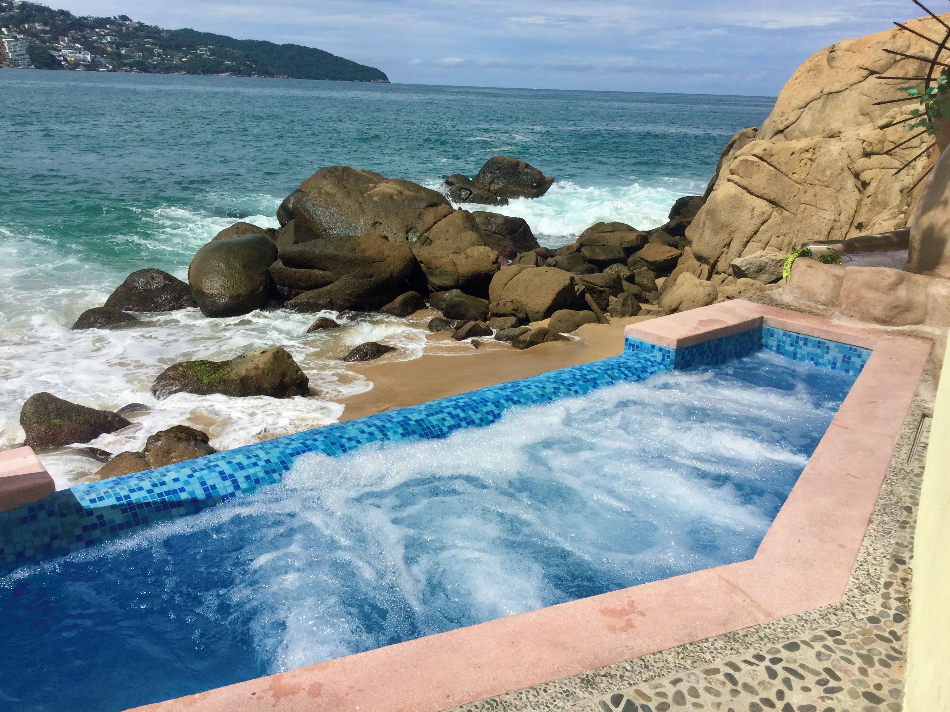 Un jacuzzi con vista al océano y a las rocas.