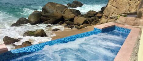 Un jacuzzi con vista al océano y a las rocas.