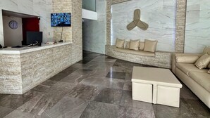 En moderne lobby med reception, siddeområde og et stort vægmonteret skærmbillede.