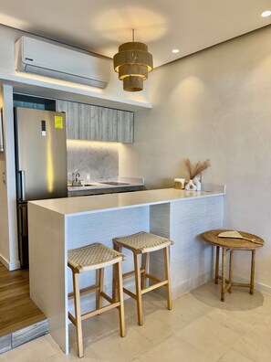 Een moderne keuken met een inbouweiland, een roestvrijstalen koelkast en een hanglamp.