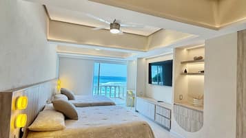 Quarto moderno com uma cama grande, ventilador de teto e vista para o oceano.