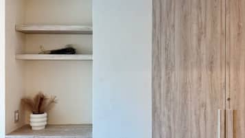 Interior minimalista com prateleiras embutidas, detalhe curvo em madeira e guarda-roupa de madeira.
