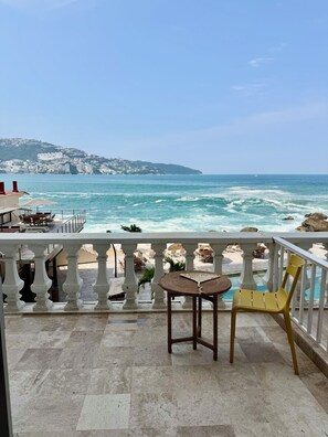 Een balkon met uitzicht op zee, een stoel en een tafel.