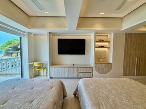 Een hotelkamer met een groot bed, een bureau, een aan de muur bevestigde televisie en uitzicht op het groen.