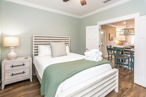 A bedroom with a bed, nightstand, and a view into the kitchen area. - 6011 Rookery 3 Four Shores close to beach (Gulf Shores)