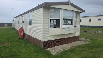 A mobile home with a front porch, a visible window, and a gas cylinder.