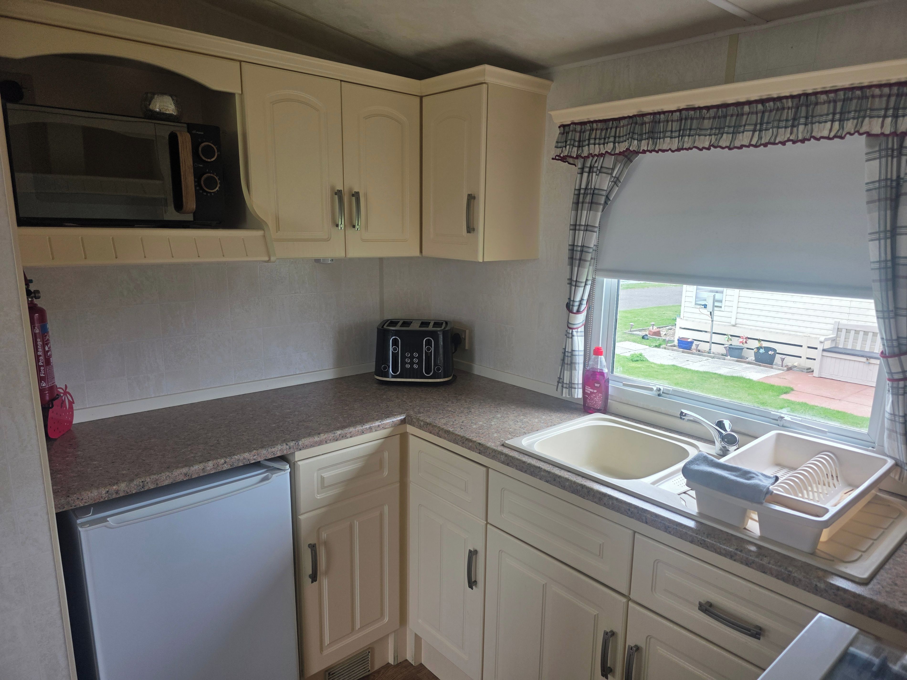 A compact kitchen with a microwave, toaster, and sink.