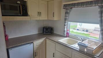 A compact kitchen with a microwave, toaster, and sink.