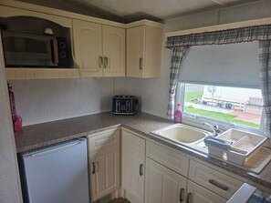 A compact kitchen with a microwave, toaster, and sink.