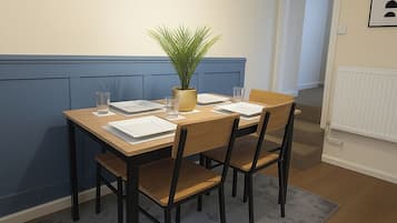 Un comedor con una mesa de madera, cuatro sillas, un tapete gris y dos decoraciones hexagonales con plantas.