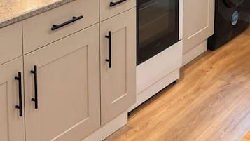 A kitchen with a gas stove, oven, microwave, and a washing machine.