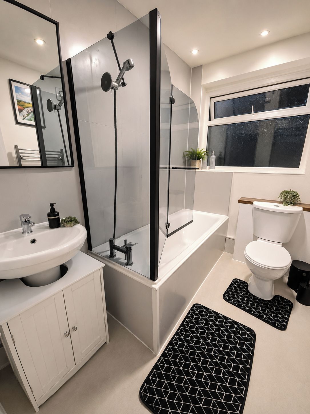 Une salle de bain moderne avec une douche à parois de verre, un lavabo blanc et des toilettes.