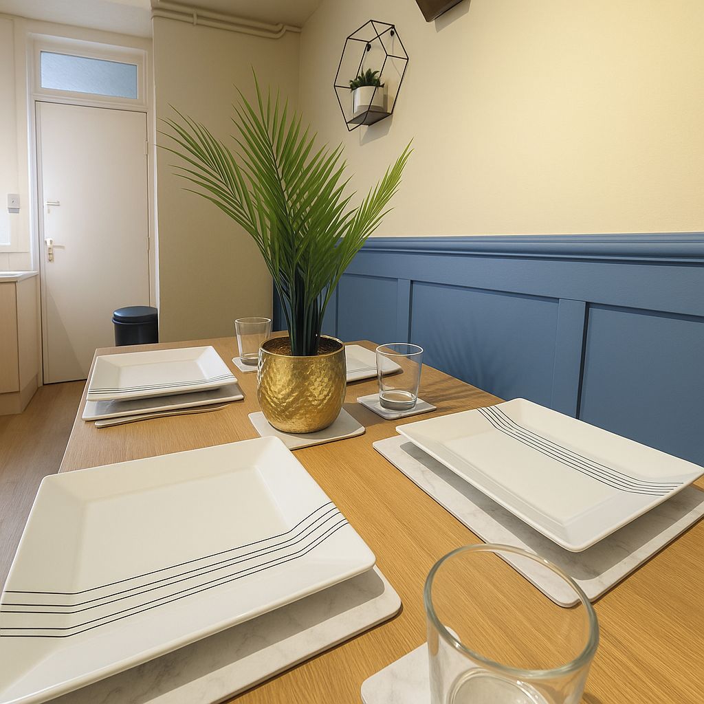 A dining table set with white plates, a gold pot, and a potted plant.