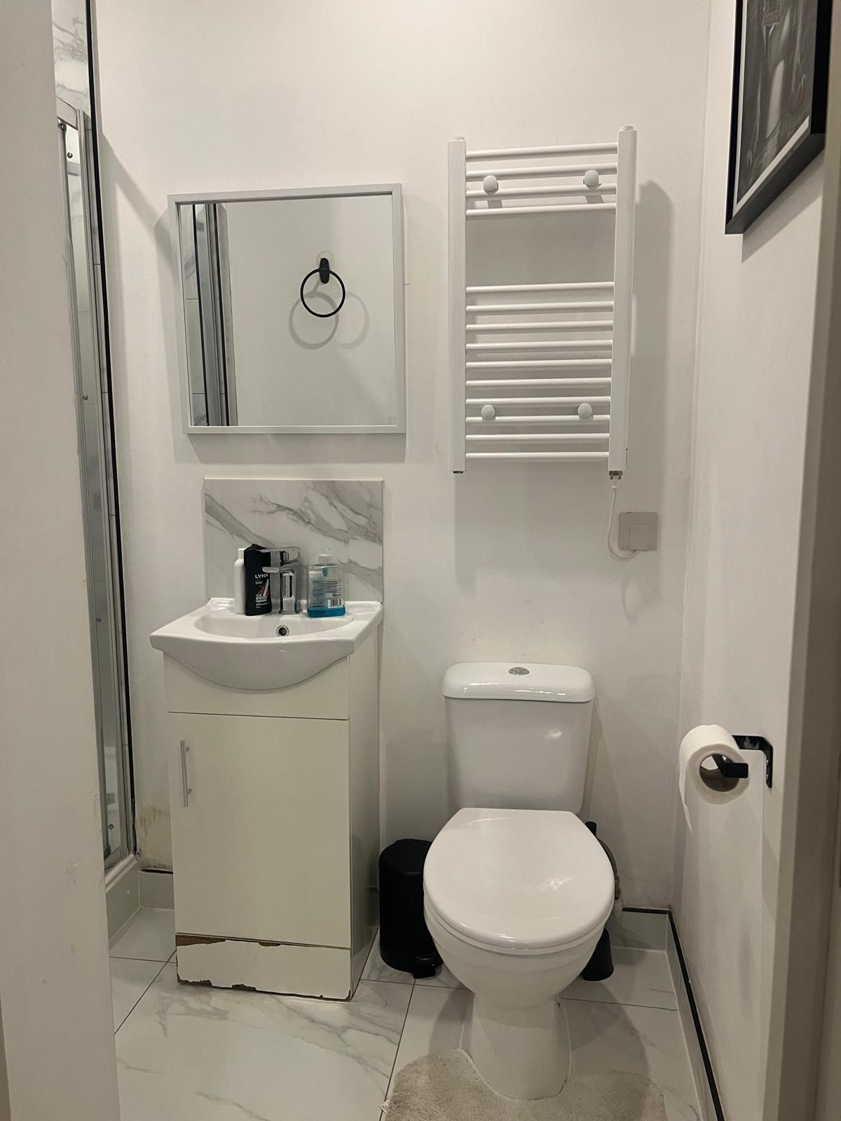 Ein kleines Badezimmer mit einem weißen Waschbecken, einer Toilette und einem Handtuchhalter.