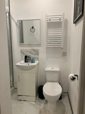 Un bagno compatto con lavandino, water e porta asciugamani bianchi.
