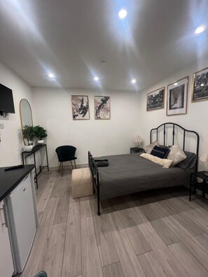 A bedroom with a bed, bedside tables, a desk, a chair, and artwork on the walls. - Barn Conversion Sleeps 2 with Wifi (Thornton Heath)
